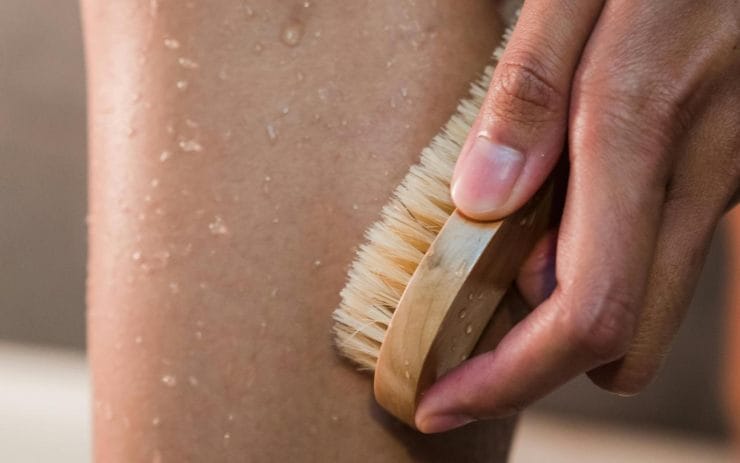 Četkanje kože nogu pod tušem za uklanjanje mrtvih ćelija pre depilacije