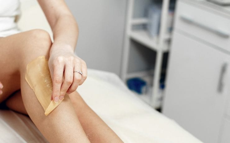 Skidanje čvrstog voska sa noge tokom profesionalne depilacije