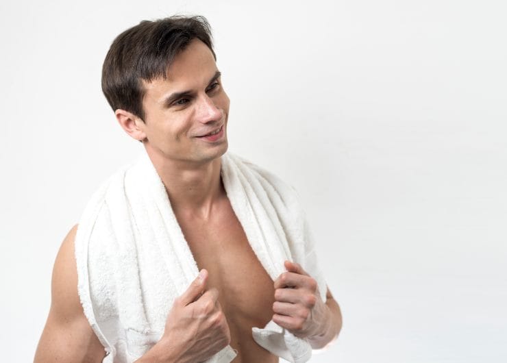 Zadovoljan muškarac sa peškirom oko vrata nakon završenog tretmana depilacije