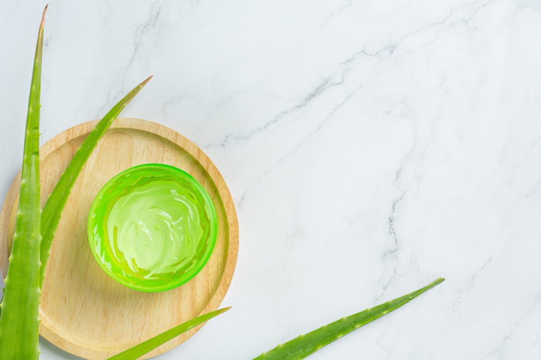 Aloe vera gel u posudi na drvenom tanjiru sa svežim listovima aloe